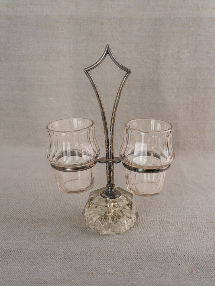 Antique French silver plate and cut glass condiment server with two vintage cups on beige fabric.