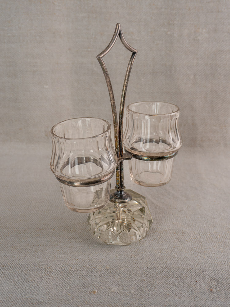 Antique French condiment server with clear glass cups, silver plate frame, cut glass base on grey fabric.