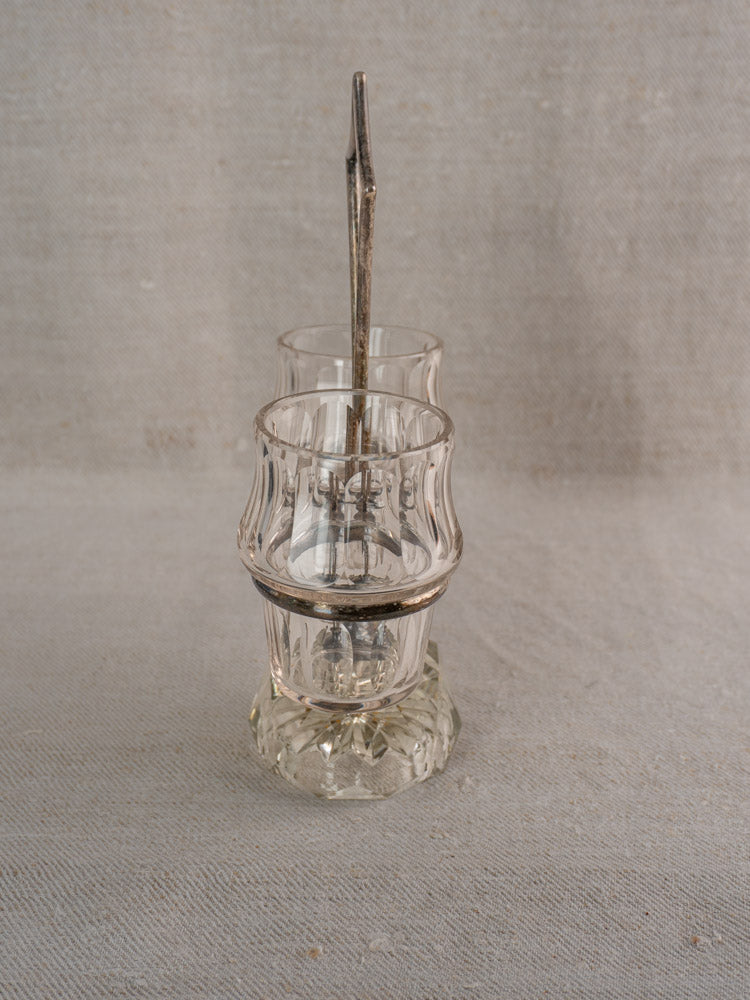 Clear textured cut glass condiment cups with silver plate base and spoon, stacked on neutral fabric background.