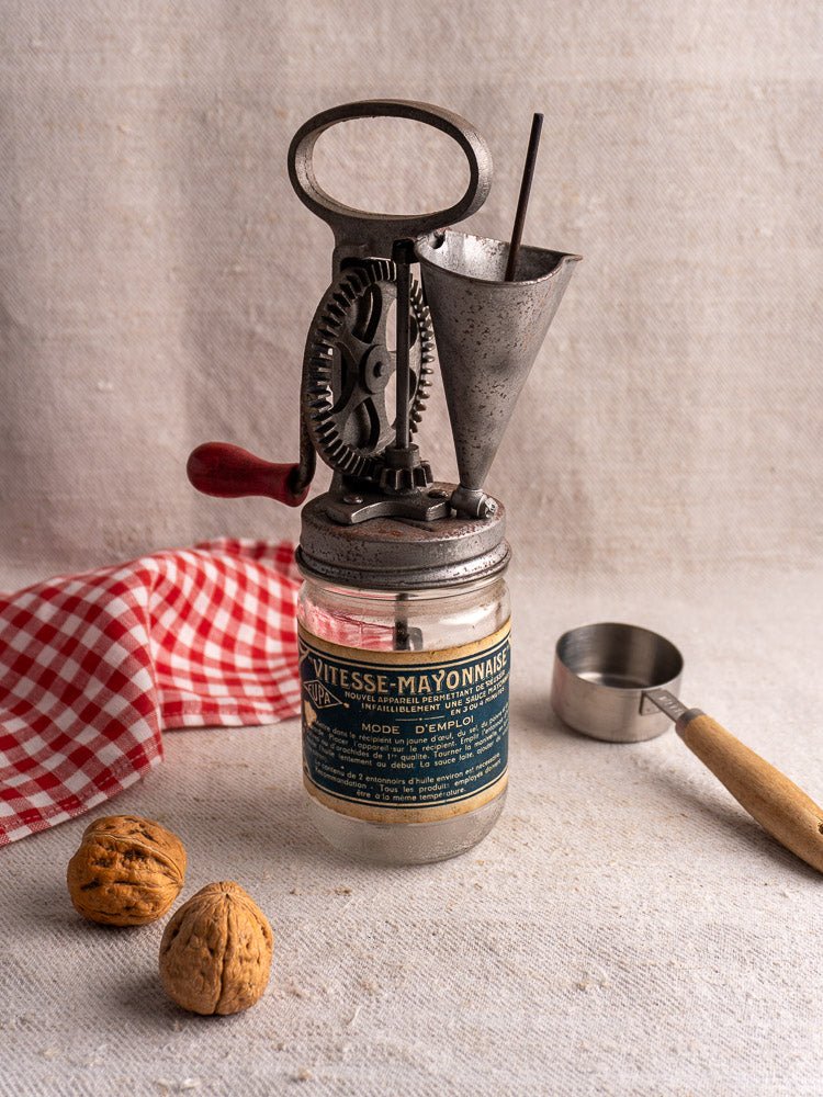 Antique French FUPA Vitesse Baratte mayonnaise maker with metal cup and walnuts on checkered cloth.