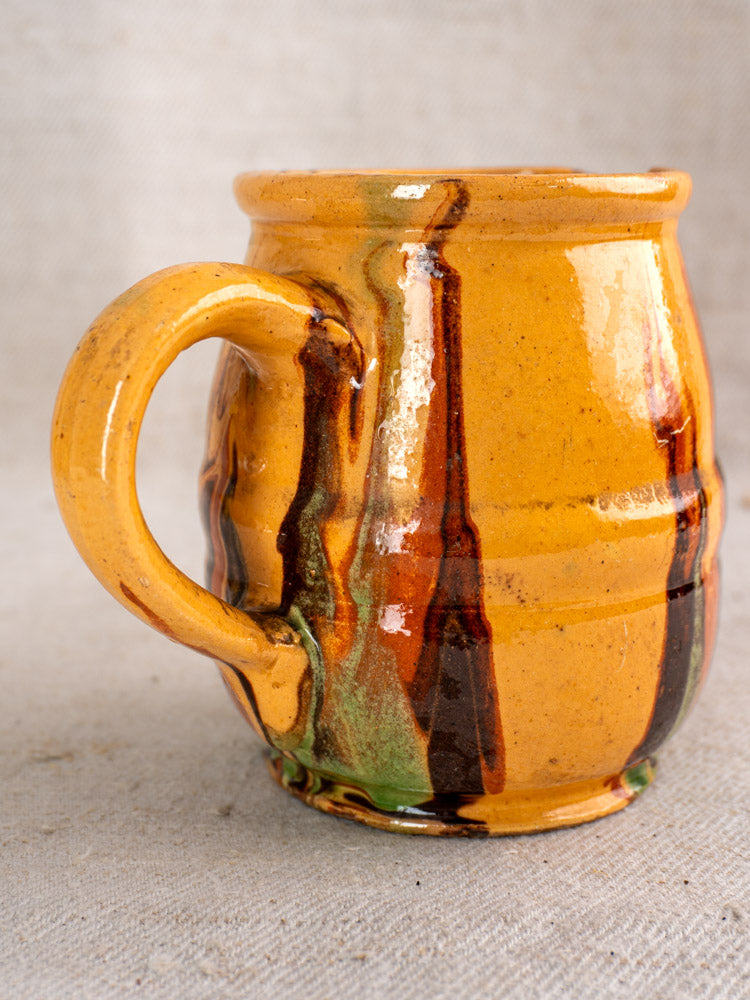 Antique French Jaspé ceramic pitcher with glossy slip glaze and yellow, brown, green, and dark orange vertical streaks.