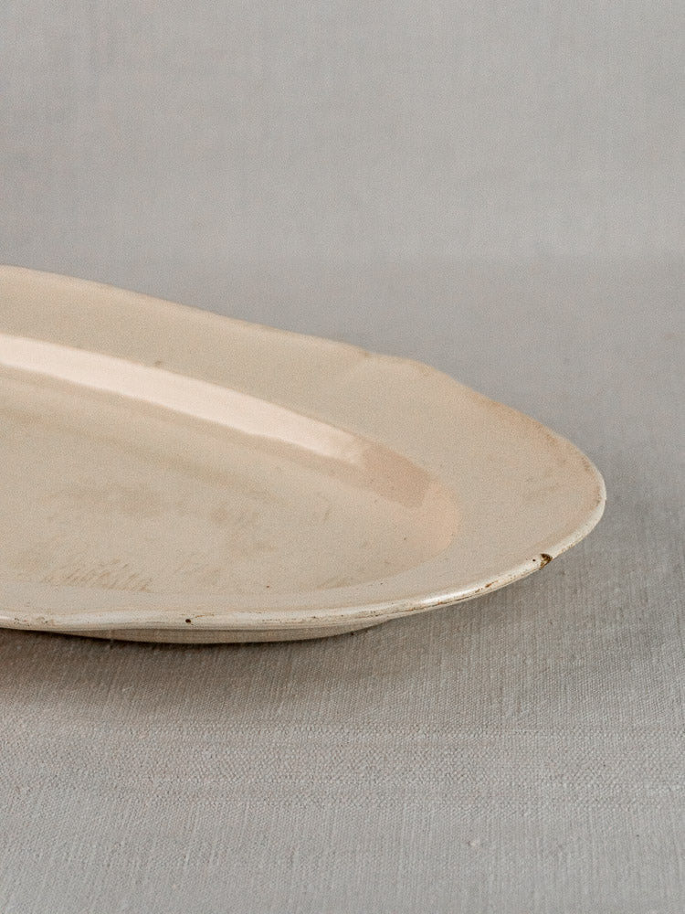 Antique French faience grand meat platter with subtle wear on off-white ceramic, light textured background.