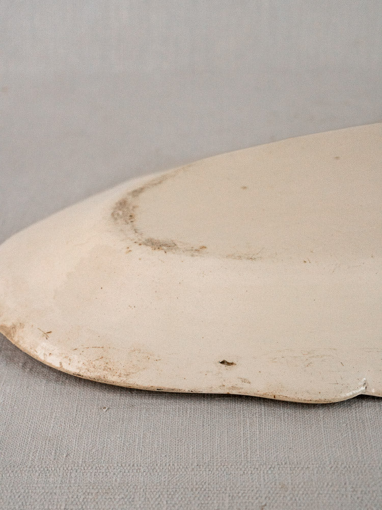 Back of antique French faience meat platter with chipped edges and subtle stains on ceramic.