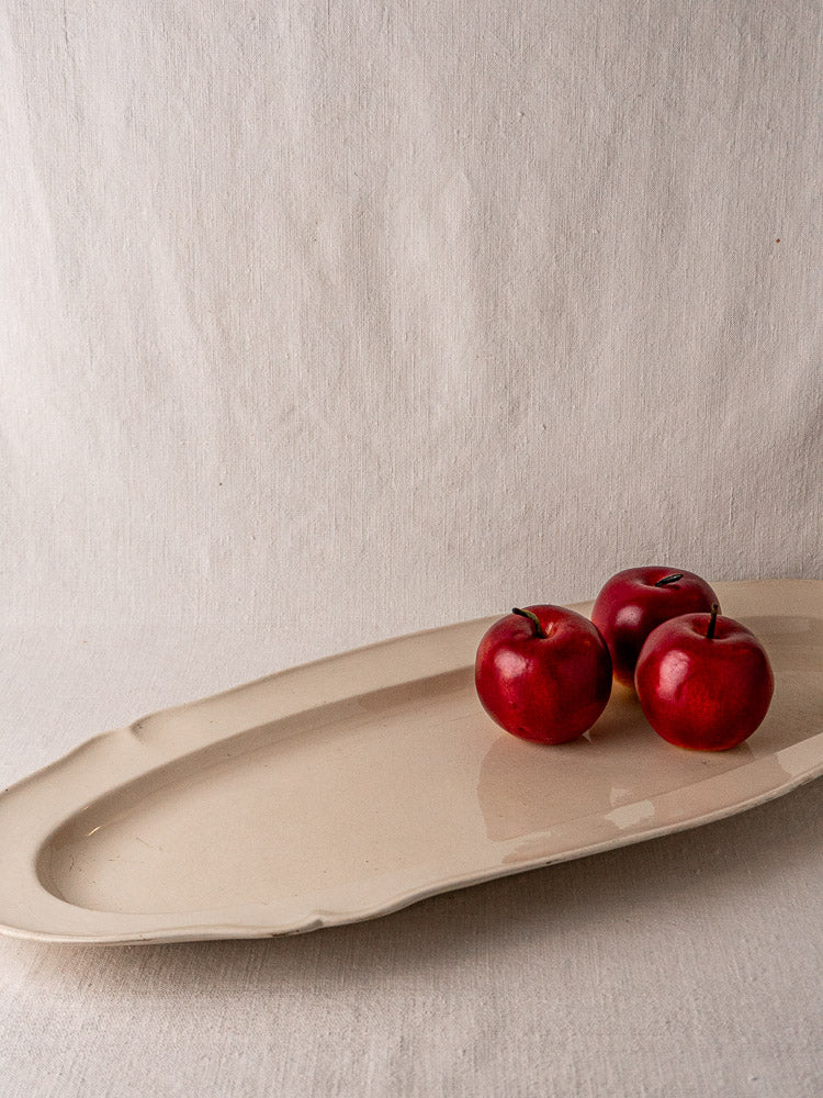 Antique French faience oval meat platter with raised rim on black stand, light background.