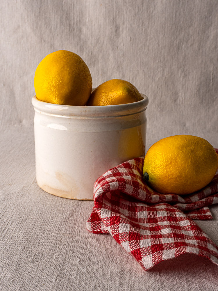 Antique French Fenal Badonviller rillettes pot in white ironstone with lemons, on red check cloth.