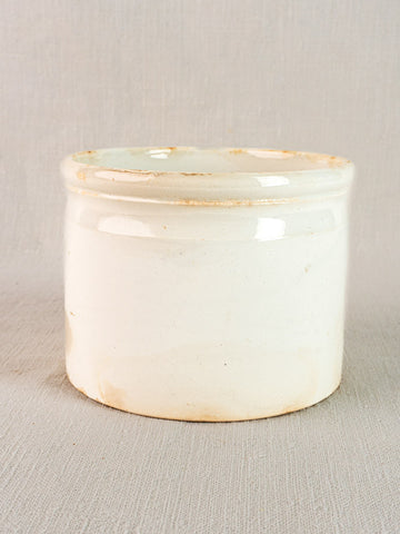 Antique French Fenal Badonviller white ironstone rillettes pot with tan base staining on textured surface.
