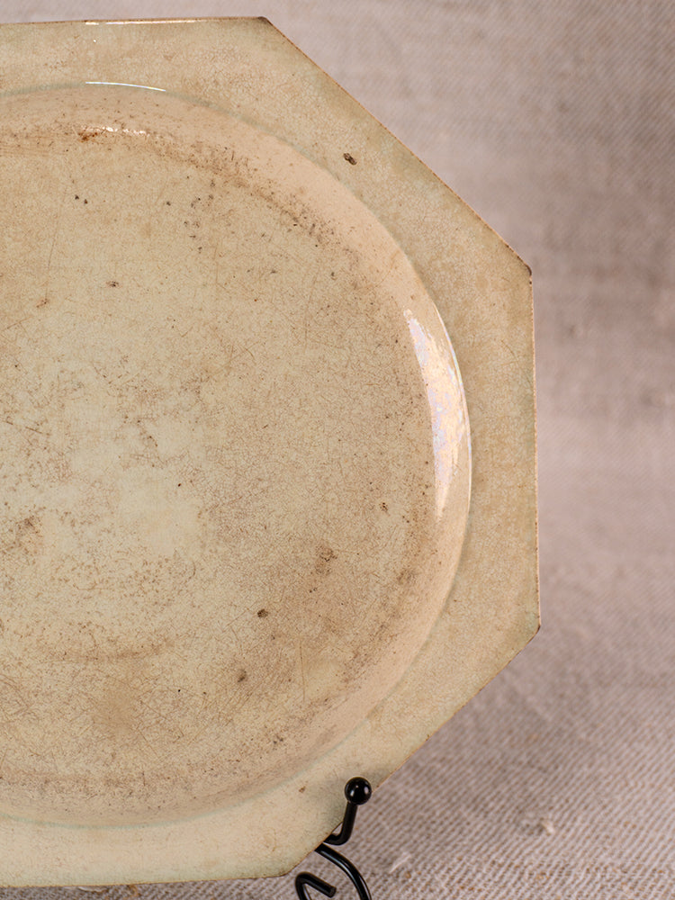 Antique French faience plate from Aumale with beaded rim, displayed on black metal stand.