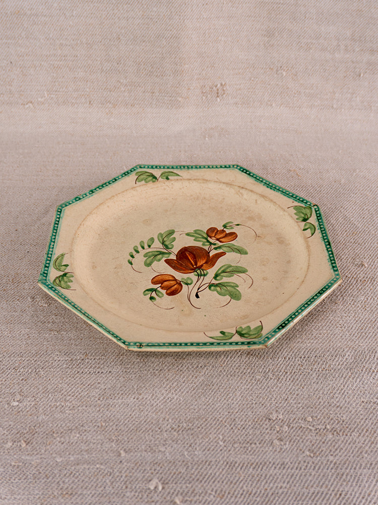 Antique French Aumale faience plate with beaded rim, green border, and floral motif on beige surface.