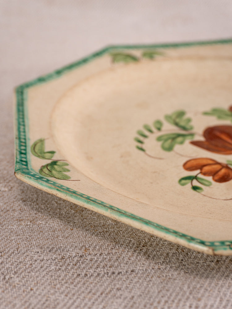 Antique French faience plate from Aumale with beaded rim, green border, and floral motif on beige surface.