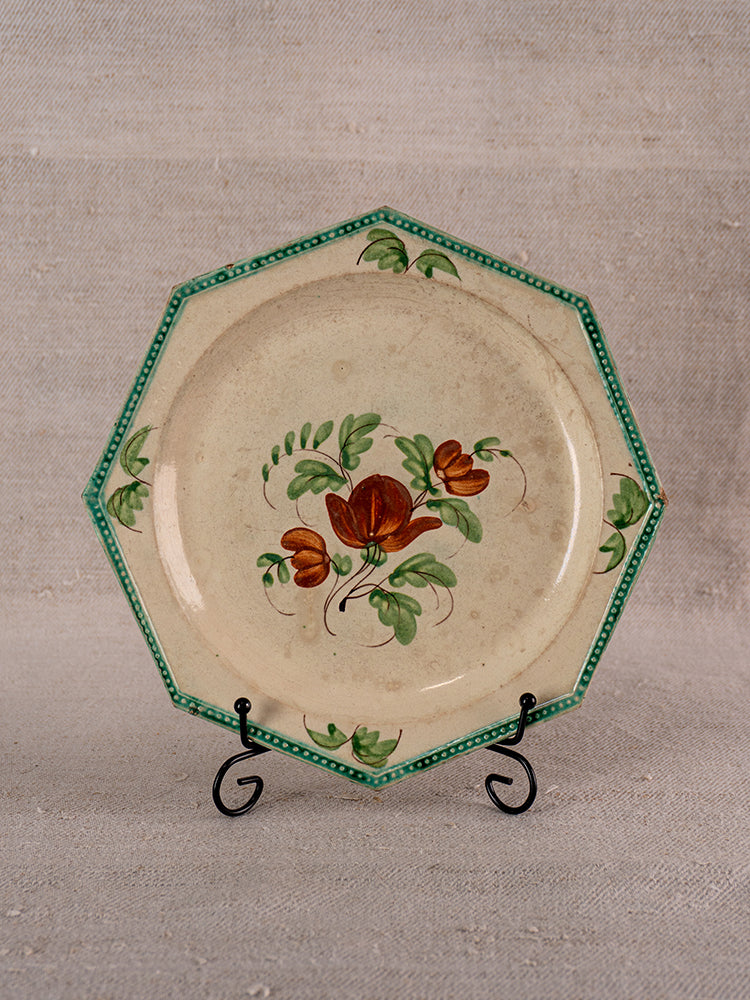 Antique French faience plate, octagonal with green beaded rim and hand-painted red floral design, on metal stand.