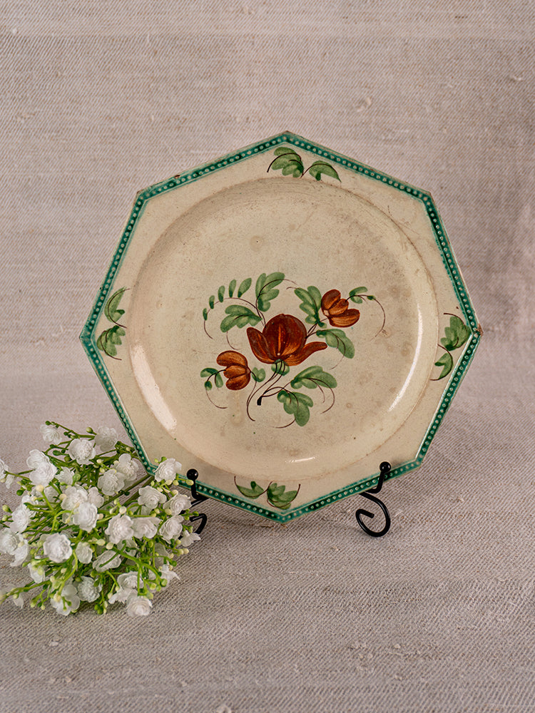 Antique French faience plate with beaded rim, green trim, and red floral motif on stand.