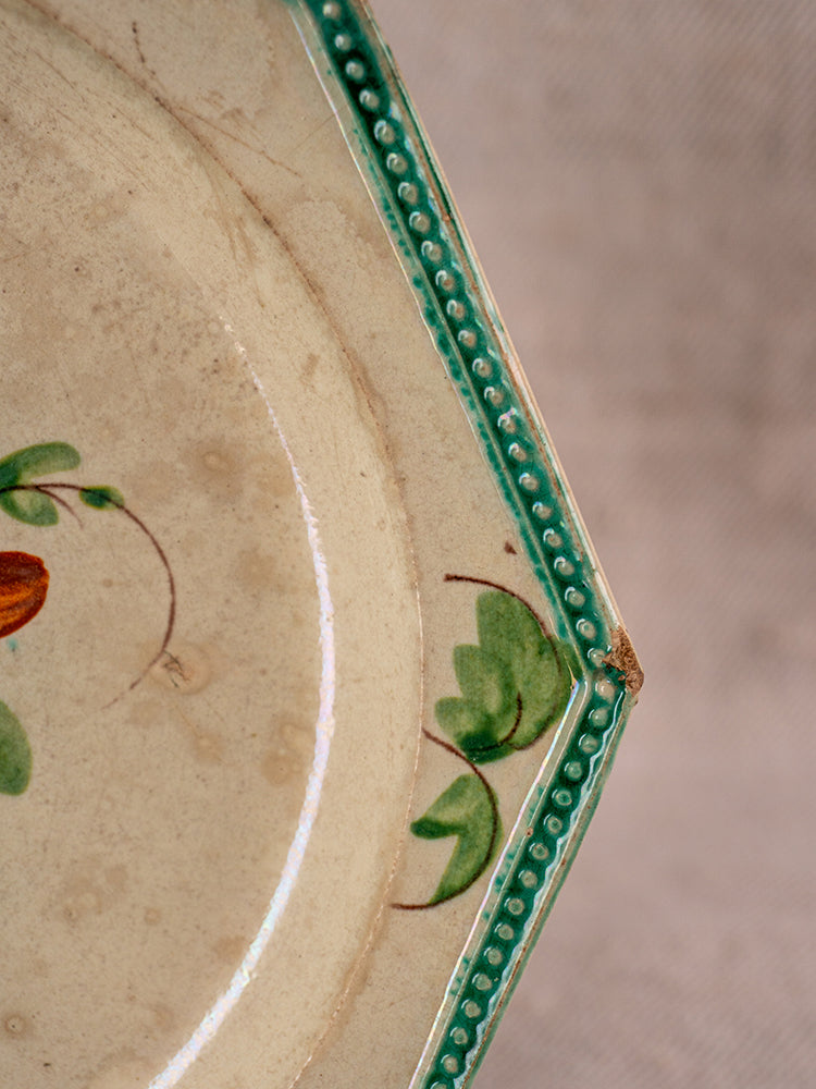 Antique French faience plate from Aumale with teal beaded rim, hand-painted floral motif, and aged wear.