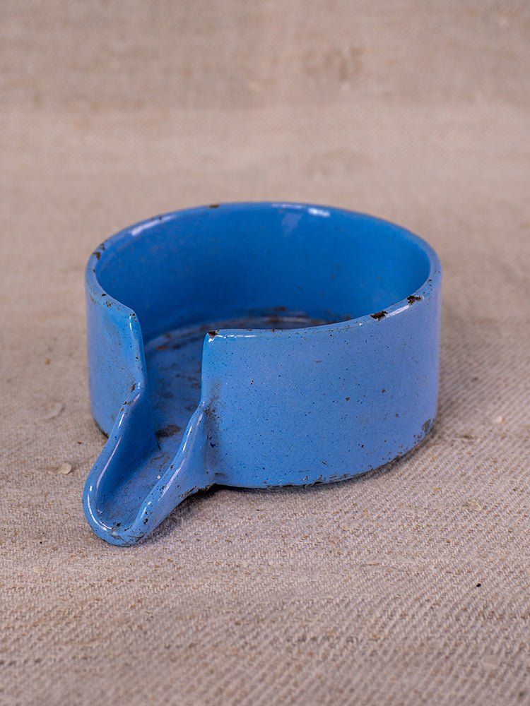 Antique French cast iron fruit press in blue enamel, circa 1900, on textured beige fabric.