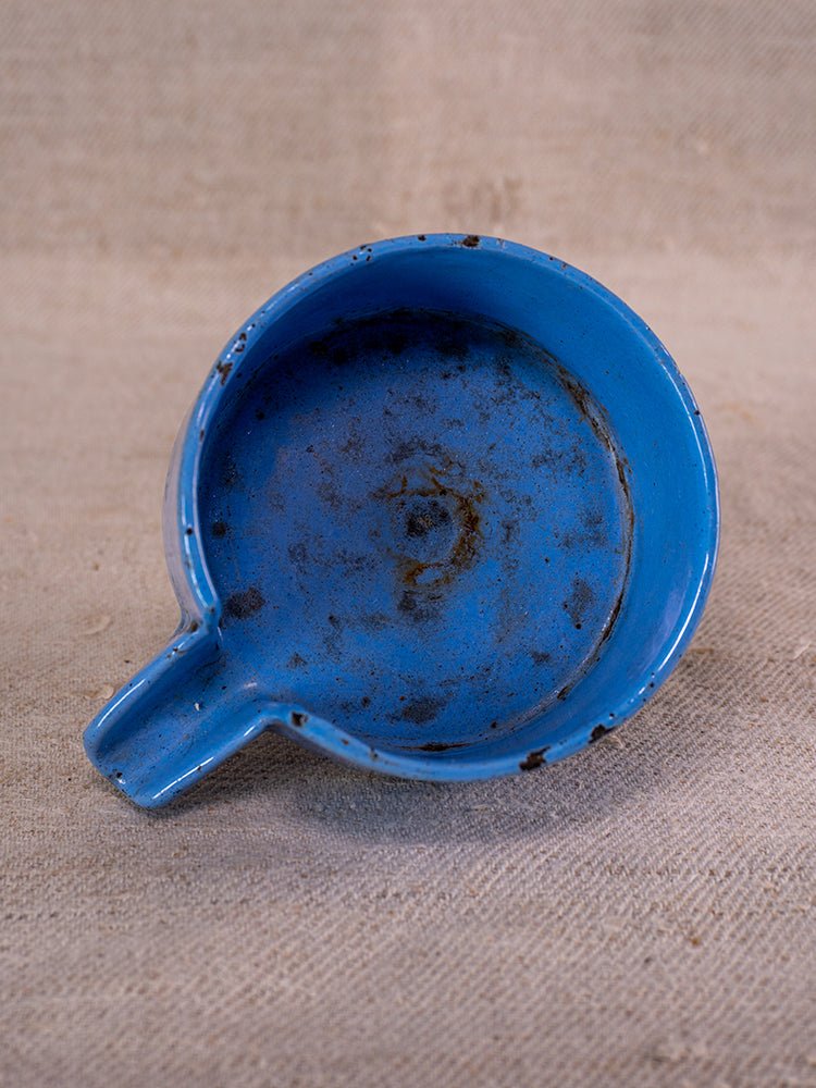 Antique French fruit press in cast iron and blue enamel with spout and visible rust.