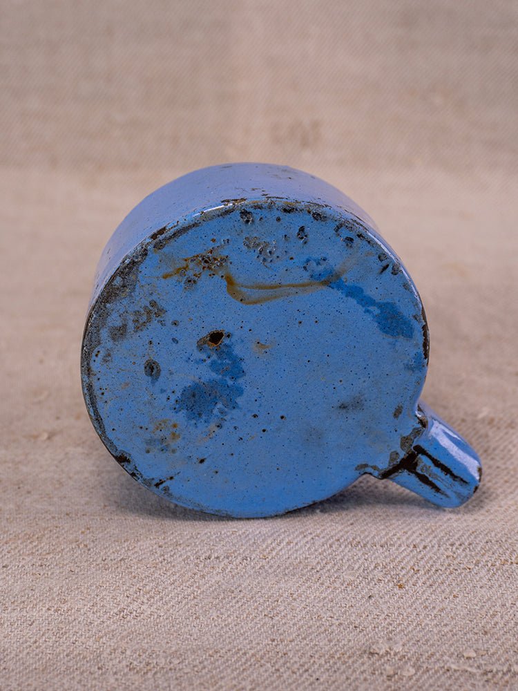 Antique French cast iron fruit press with blue enamel, c.1900, on textured beige fabric.