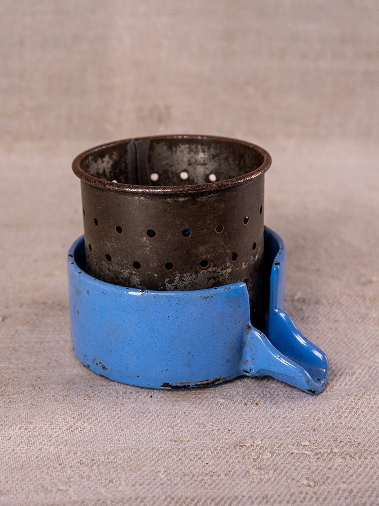Antique French cast iron fruit press with blue enamel accents, circa 1900, on beige textured surface.