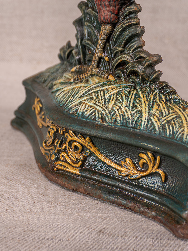 Antique French cast iron rooster doorstop base with green and gold scrollwork, textured grass, and clawed foot.