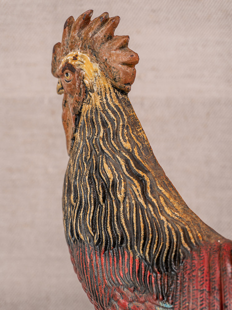 Antique French cast iron rooster doorstop with polychrome brown, gold, and red feathers on neutral background.
