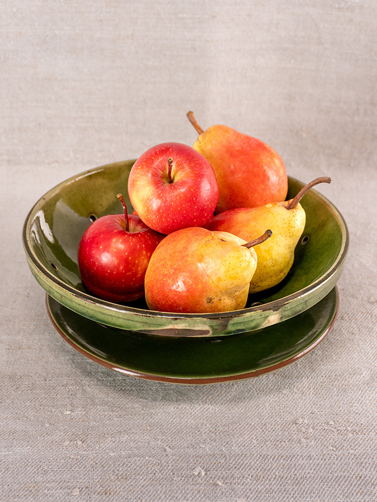 Antique French green glazed earthenware berry drainer set with bowl and plate, apples and pears on beige background.