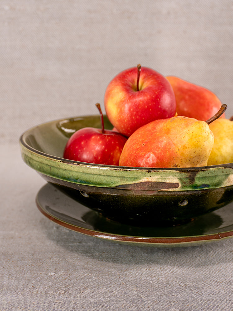 Antique French green glazed earthenware berry drainer set with red apples and yellow pears on matching plate.
