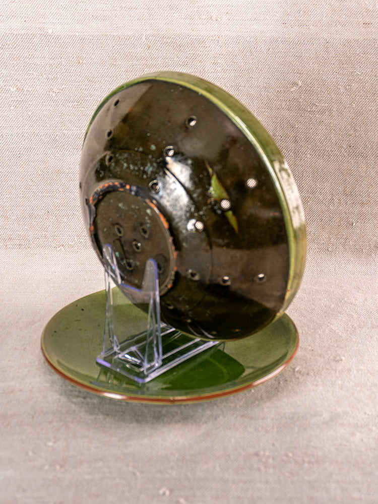 Antique French green glazed earthenware berry drainer set, upright and flat on textured neutral fabric.