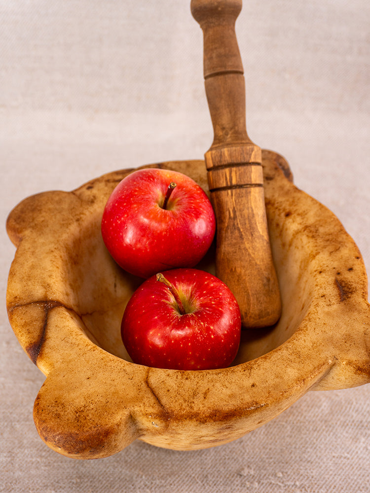 Antique French marble mortar and pestle with Provencal silhouette on textured beige fabric, showcasing aged patina.