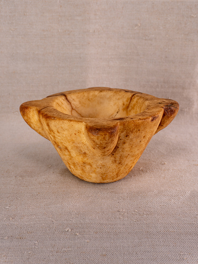 Antique French marble mortar and pestle with Provencal silhouette on a neutral fabric backdrop.