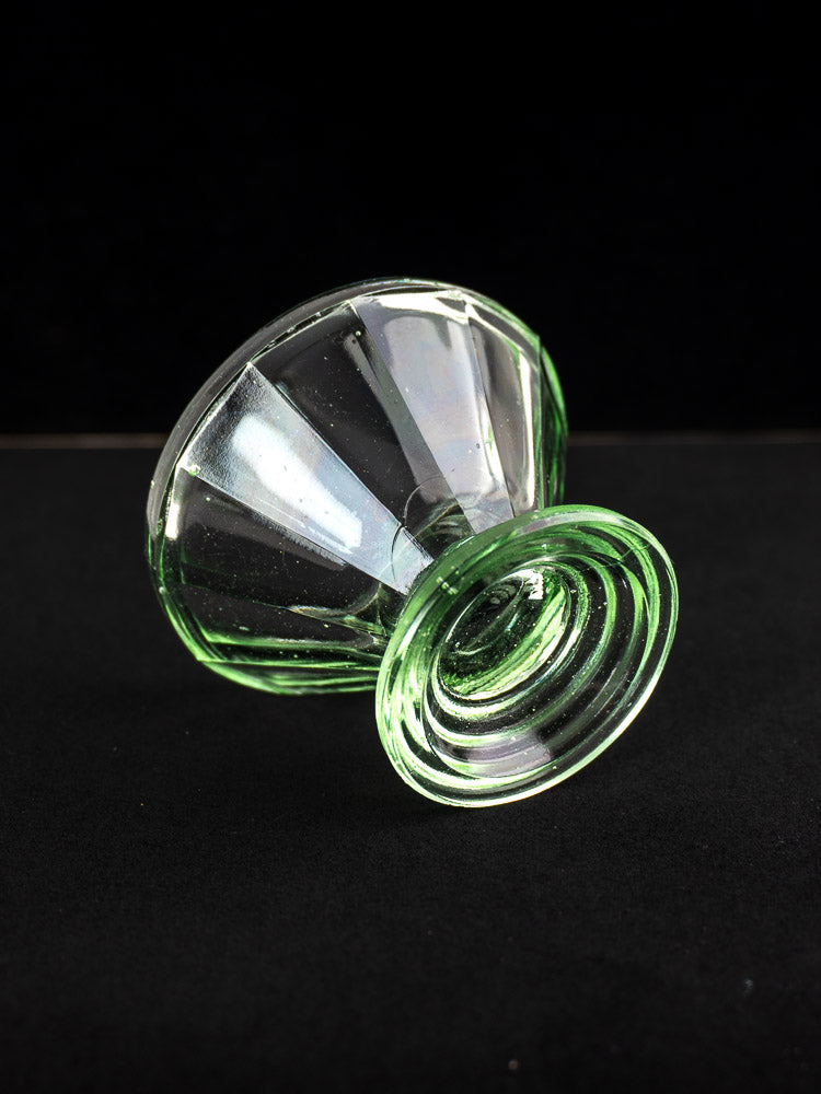 Antique French uranium glass Art Deco sherbet coupe with fluted bowl and ridged base on black background.