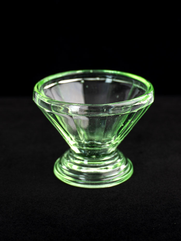 Set of 12 antique French Art Deco uranium glass sherbet coupes with clear green flared bowls and sturdy bases on black backdrop.