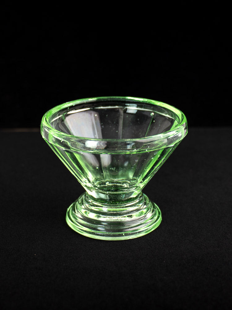 Set of 12 antique French uranium glass sherbet coupes with flared rims and pedestal bases in Art Deco style, on black background.