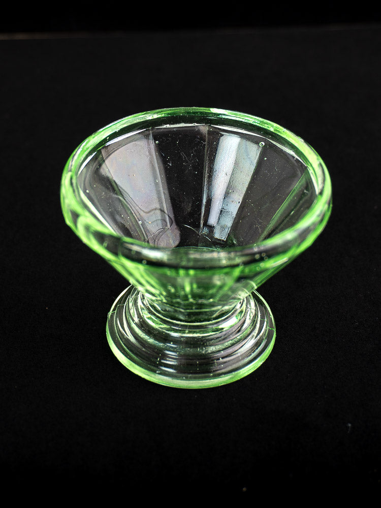 Set of 12 antique French uranium glass sherbet coupes with green Art Deco bowls and round bases on black background.