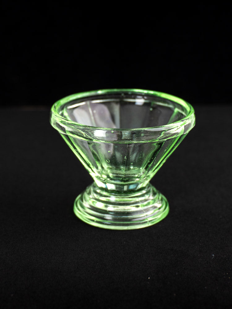 Set of 12 antique French Art Deco uranium glass sherbet coupes with flared green bowls and pedestal bases on black background.