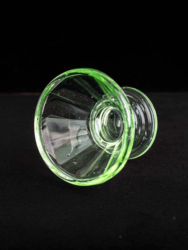 Antique French uranium glass sherbet coupe with transparent green Art Deco design, flared rim, on black background.