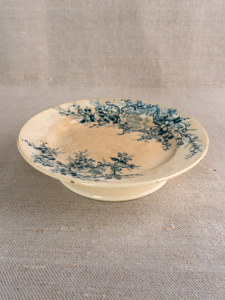 Antique French compote plate by Boulenger Choisy-le-Roi, Pompadour blue floral on cream, on beige textured fabric.