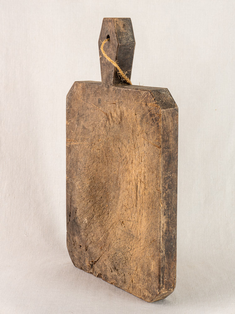 Antique French hand carved cutting board, circa 1850, with diamond handle and visible aged patina, upright against light background.