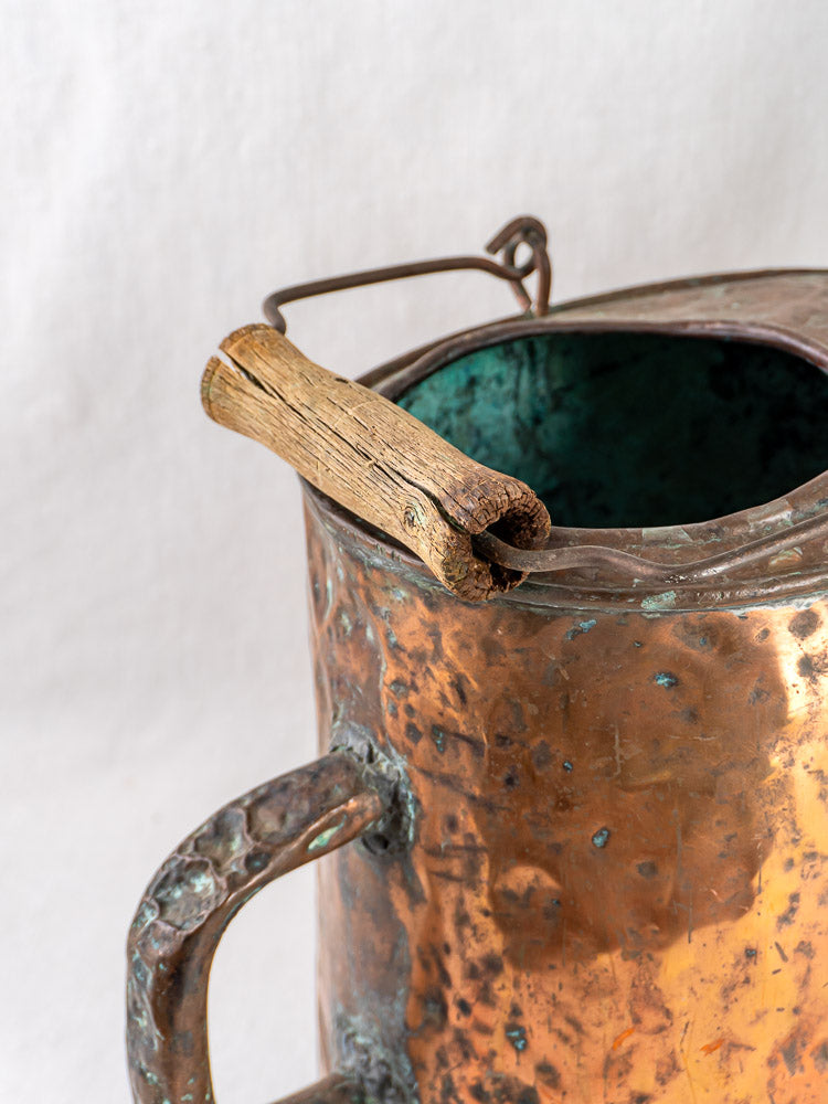 French 19th-century hammered copper water carrier with weathered wood handle and green patina interior.