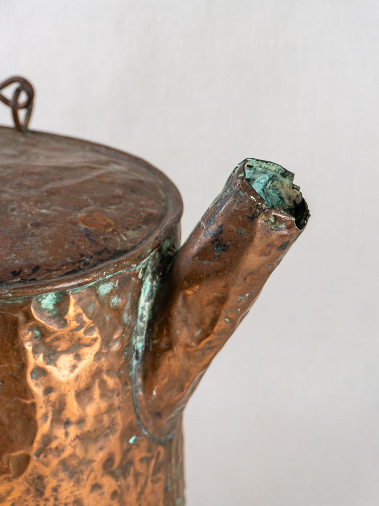 19th-century French hammered copper water carrier with weathered surface and corroded spout on light background.