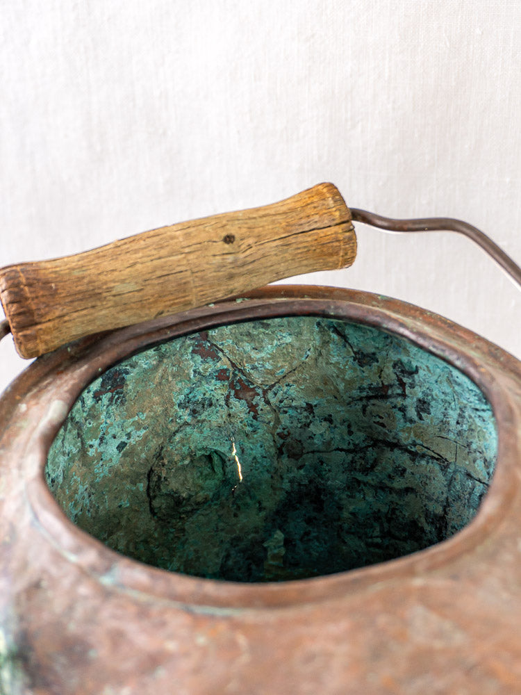 French 19th-century hammered copper water carrier with aged patina and curved wooden handle.