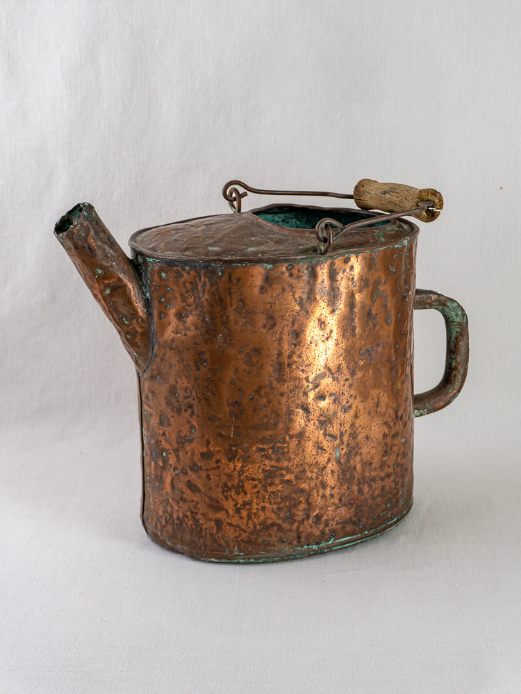 19th-century French hammered copper water carrier with textured surface, short spout, and wooden lid handle.