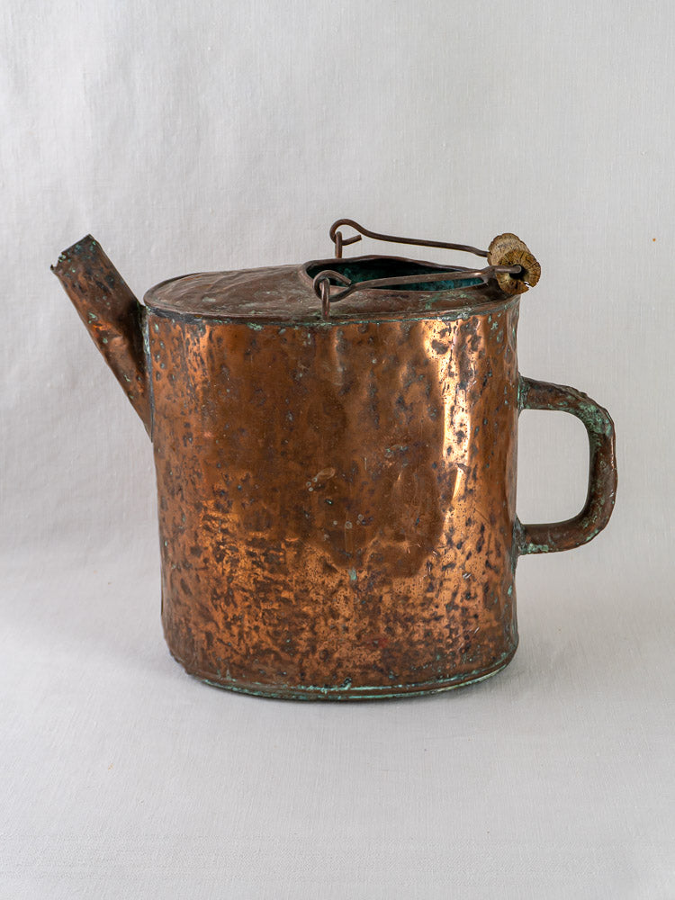 19th-century French hammered copper water carrier with side handle, short spout, and hinged lid on light background.