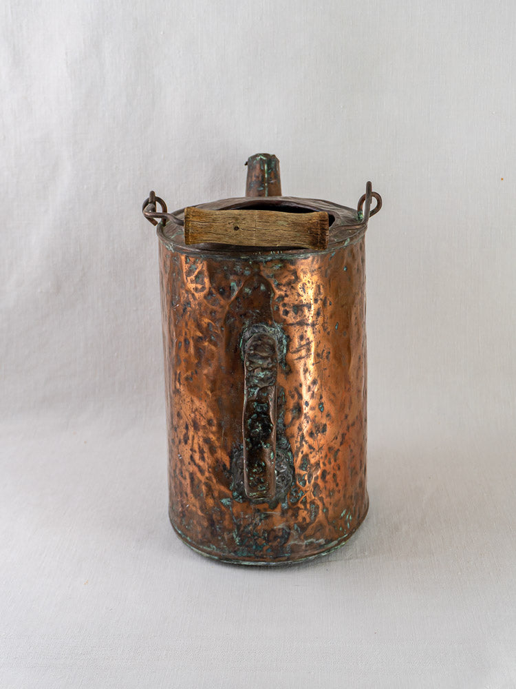 19th-century French hammered copper water carrier with side handle, spout, and wooden lid on white background.