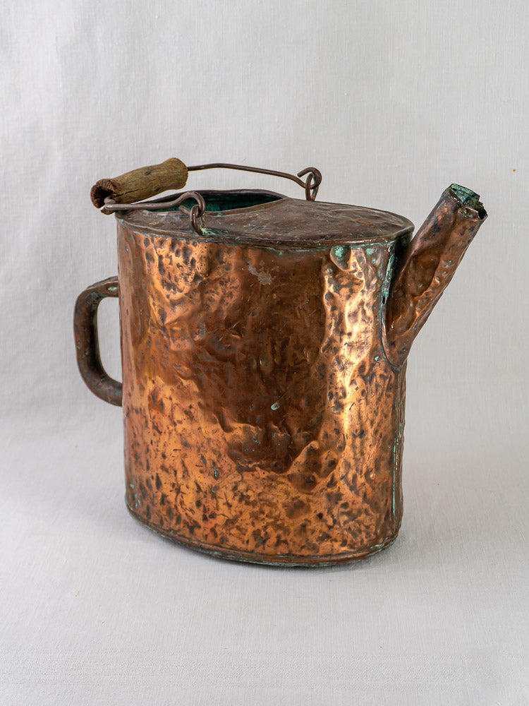 19th-century French hammered copper water carrier with wood top handle and side handle, on neutral background.
