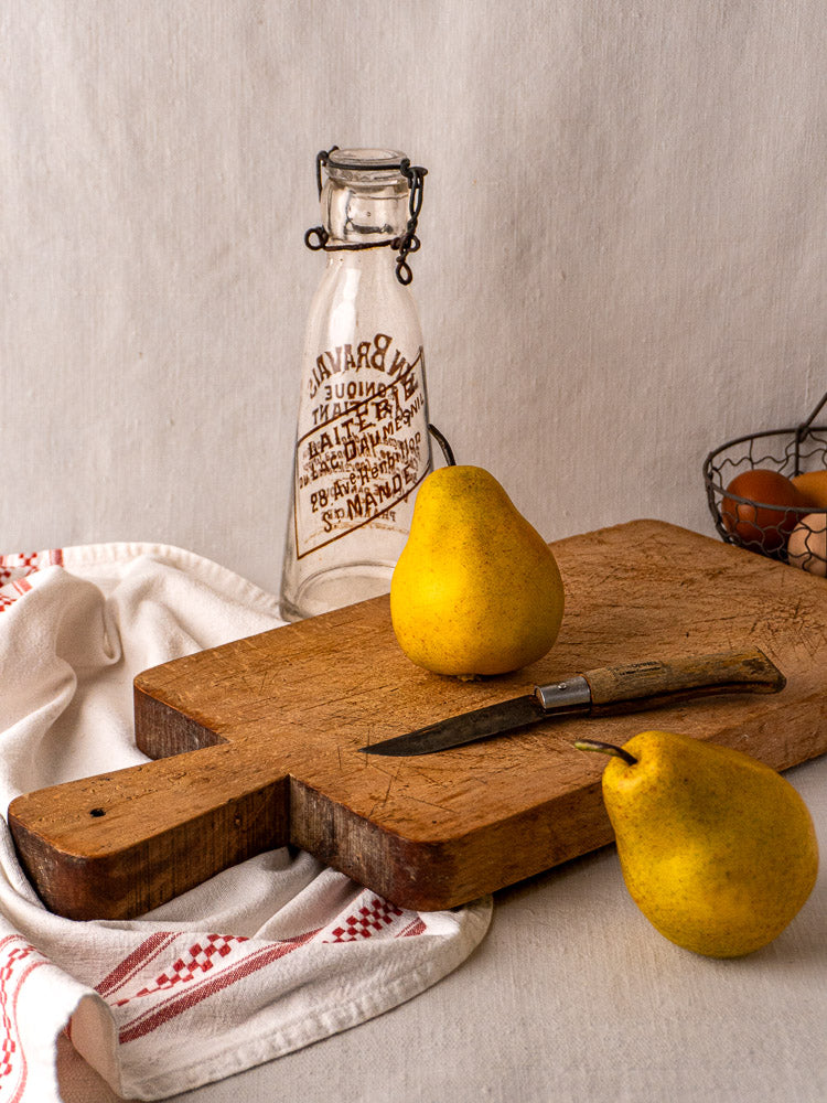 Antique French rectangular paddle handle cutting board with knife marks, upright against a light background.