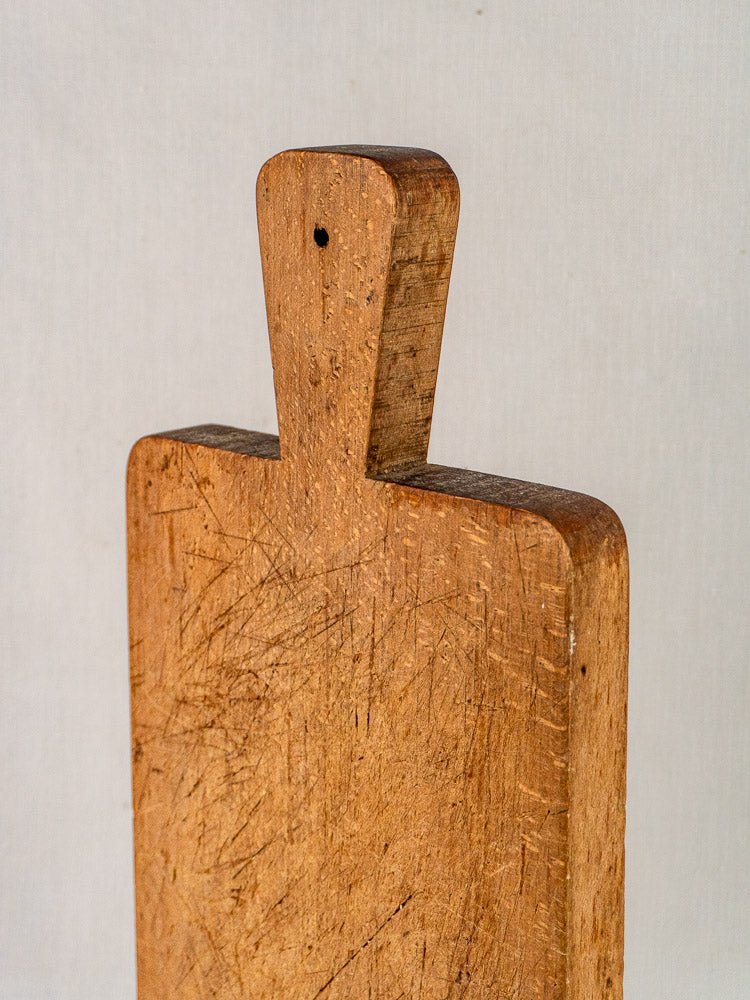 Antique French paddle handle cutting board with knife marks and hole at top, late 19th century.