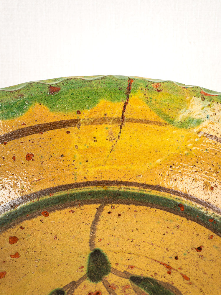 Antique French slipware bowl, 18th century, hand painted floral motifs, yellow-green glazed rim with visible crack.