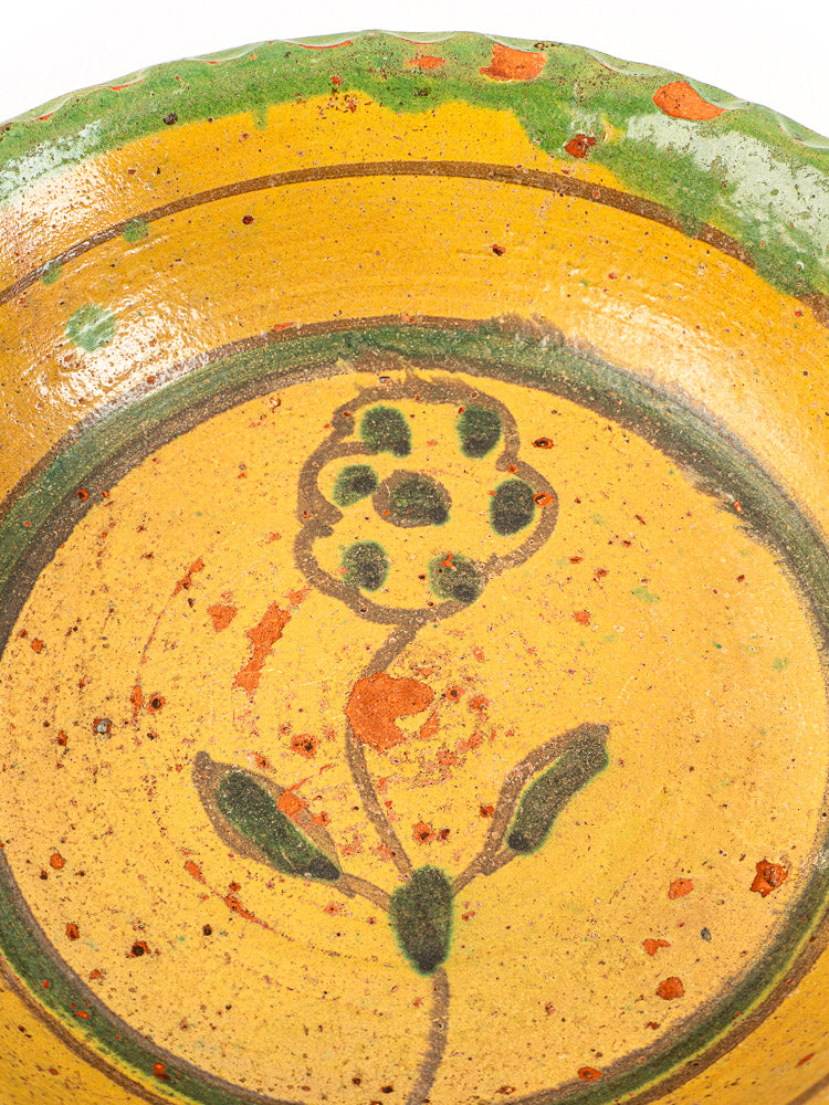 18th-century antique French slipware bowl, hand painted with green and black floral details and scalloped rim.