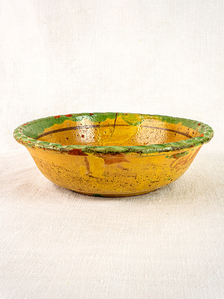 Antique French slipware bowl, 18th century, hand-painted floral design, rustic yellow glaze, green rim.