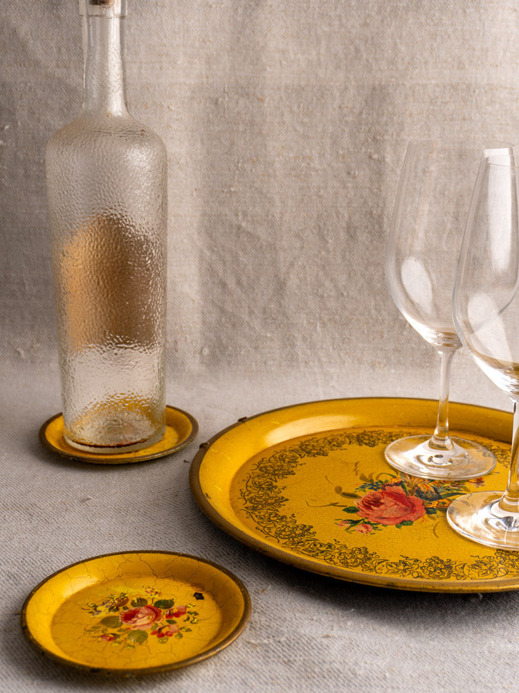 Antique French tole tray set with yellow lacquer and floral motifs, shown with glassware on neutral fabric.
