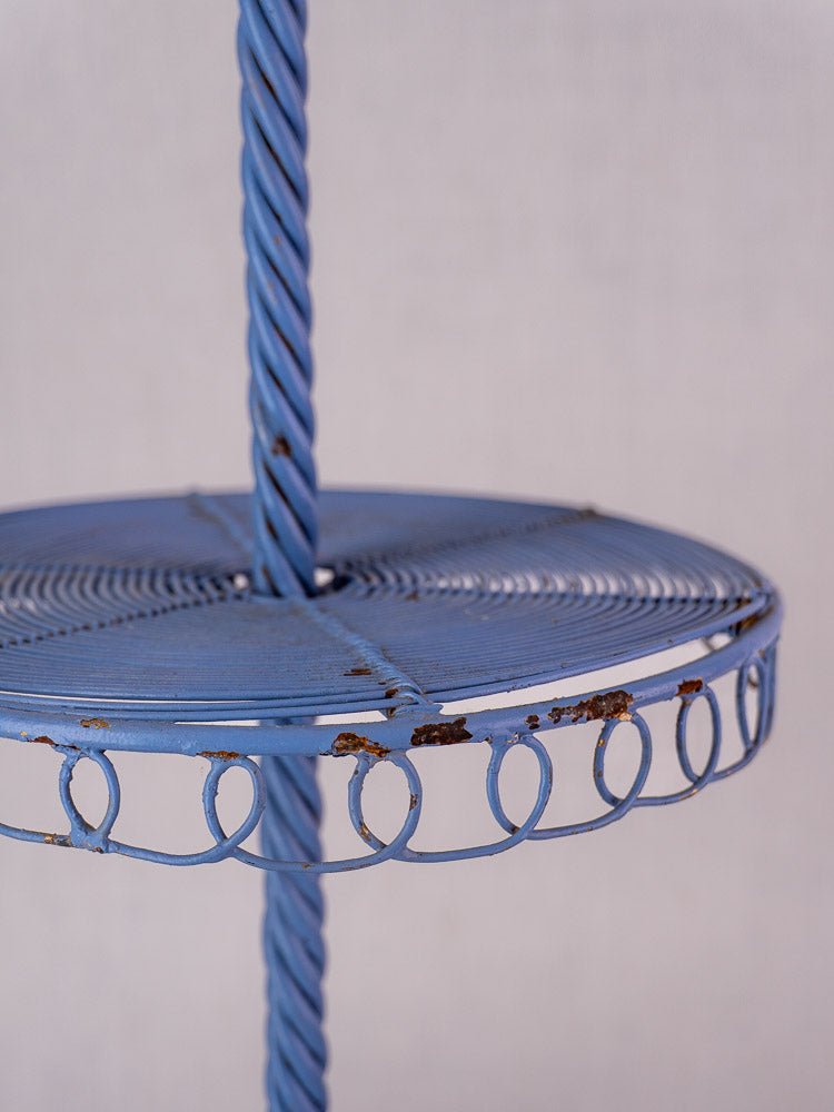 Antique French blue three-tier wirework pastry display stand with twisted pole and decorative looped rim, subtle rust details.