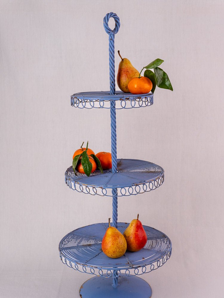 Antique French blue wirework three-tier pastry stand displaying pears and small oranges.